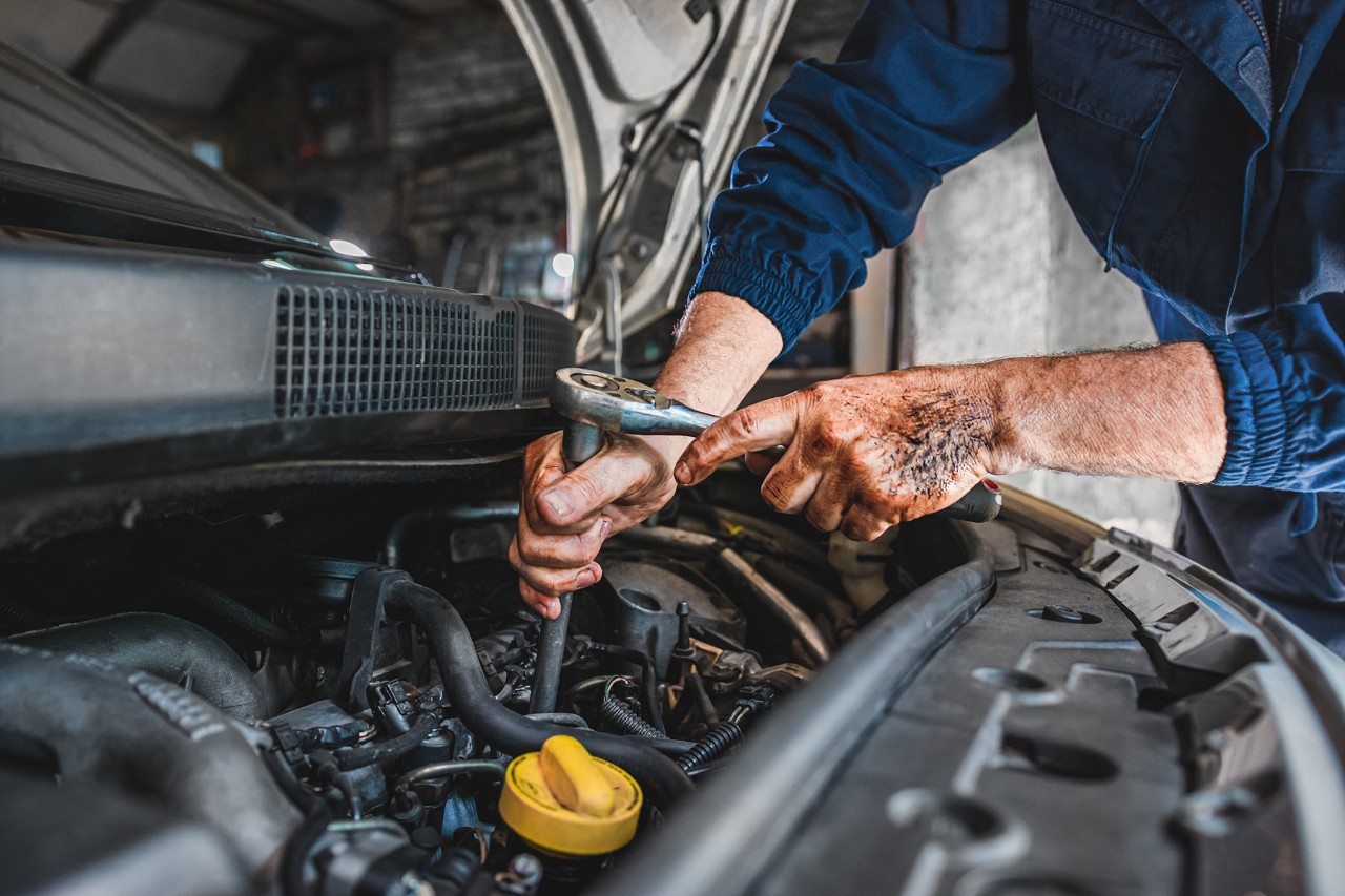 Mechanic repairing engine on a car using wrench. Close up of hands